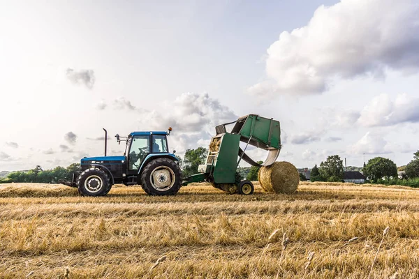 Straw Press Machine at work in a yellow field Royalty Free Stock Photos