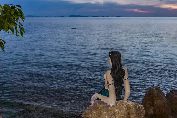 Thai Little Mermaid sits on a cliff in the sunset