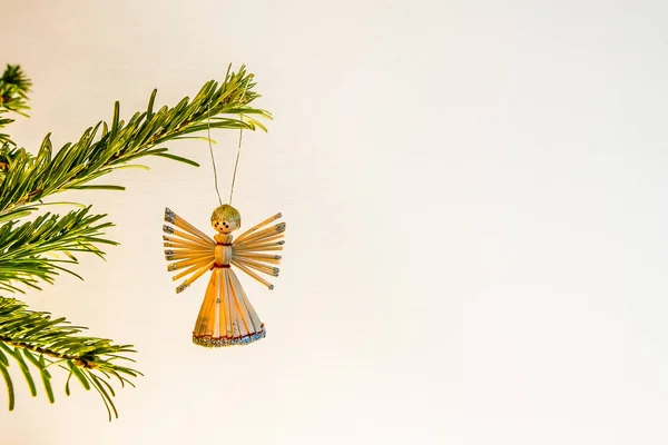 Angel made of straw, hanging in a green branch of a christmas tr — Stock Photo, Image