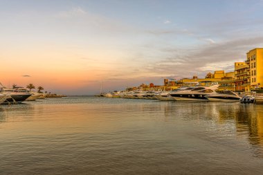 17 Ocak 2020 'de New Marina, el Gouna, Mısır' ın girişinde turuncu gökyüzü ile birlikte gün batımında sunucuda kopyası için yeri olan motorlu yatlar.