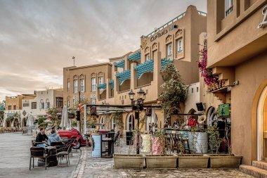 Akşam güneşinde renkli bir Arap restoranı, kaldırımda bir masada oturan kadın ve erkek, el Gouna, Mısır, 14 Ocak 2020