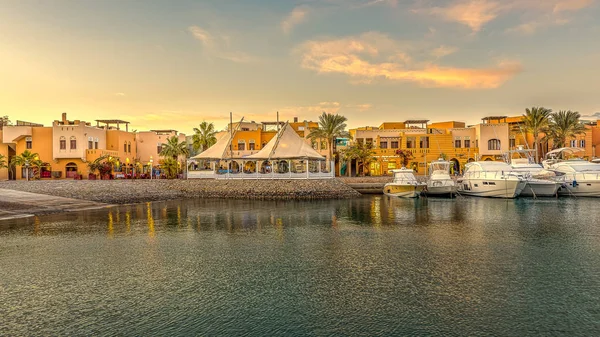 17 Ocak 2020 'de New Marina, el Gouna, Mısır' da turuncu gökyüzü ile günbatımında sunuculukta yer alan restoranlar ve motorlu yatlar.