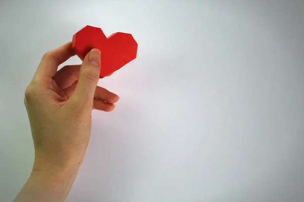 Pembe Kalp hacimli kağıt ile beyaz bir arka plan üzerinde tutan el. Sevgililer günü — Stok fotoğraf