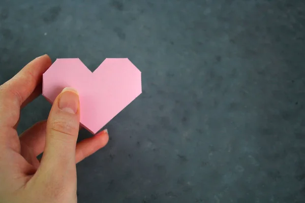 Pembe Kalp hacimli kağıt ile beyaz bir arka plan üzerinde tutan el. Sevgililer günü — Stok fotoğraf