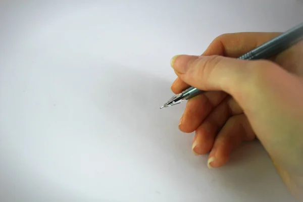 Mano femenina escribe una pluma sobre un fondo blanco — Foto de Stock