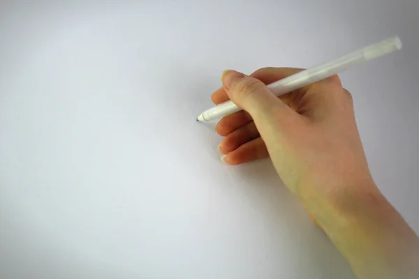 Mano femenina escribe una pluma sobre un fondo blanco — Foto de Stock
