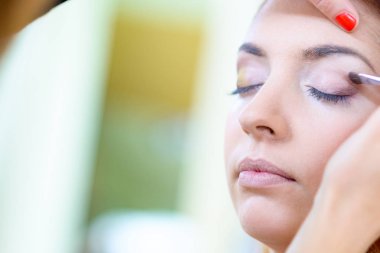 Makyaj yaparken bir güzellik salonu dalgalı saçlı Kızıl saçlı kız.