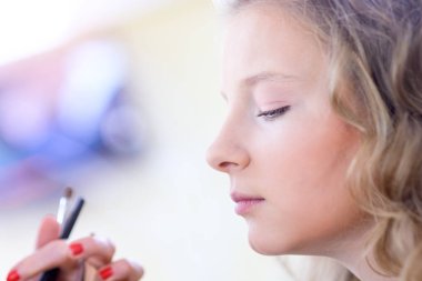 Sarışın bir kız bir güzellik salonu makyaj yapıyor. Sığ derinlik-in tarla.