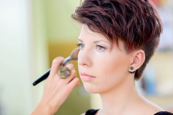 The girl with dark hair and short hair make make-up in a beauty salon. Shallow depth of field. — Stock Photo, Image