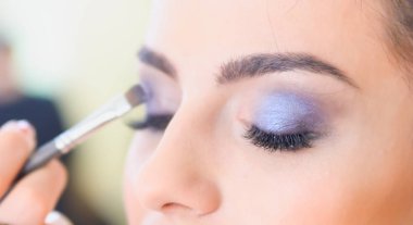 Kız bir güzellik salonu makyaj yapıyor. Çevre göz kulak odaklan. Sığ derinlik-in tarla