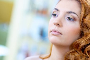 Makyaj yaparken bir güzellik salonu dalgalı saçlı Kızıl saçlı kız.