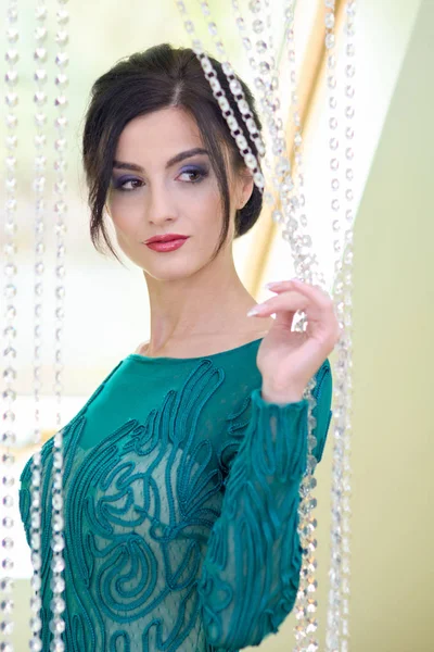 Model mit dunklen Haaren und türkisfarbenem Kleid posiert nach getaner Make-up und neuer Frisur. — Stockfoto
