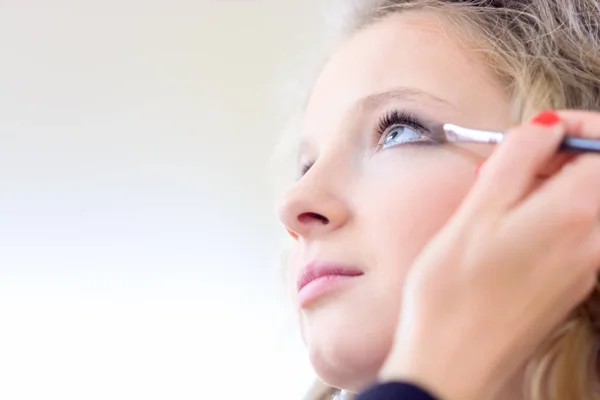 A blond girl in a beauty salon doing make-up.Shallow depth of field. — Stock Photo, Image
