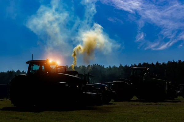 Bir traktör alanında gece gökyüzü ve duman çalıştıran motorlarından bir arka plan üzerinde dahil parlayan farlar ile silüeti. — Stok fotoğraf