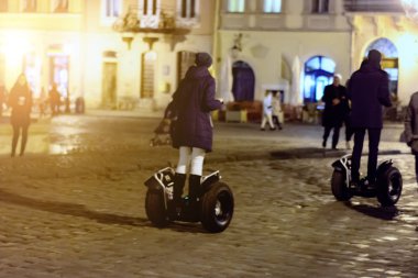 Kız ve adam gece yolda büyük bir Gyroscooter üzerinde gitmek. Tonlama. Yumuşak odak.