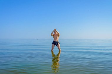 Bir adam, elinde bir bıçak ile suda bekleyen bir peştemal.