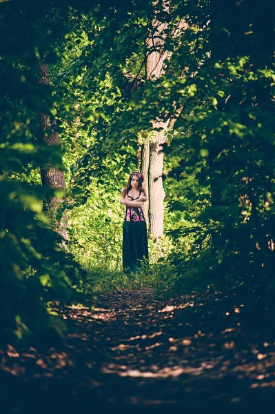 Una ragazza si trova alla fine di un percorso in una magica foresta verde. Post-elaborazione . — Foto Stock