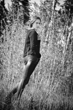 Modern kız kot pantolon ve kazak doğa arka planda. B W fotoğraf