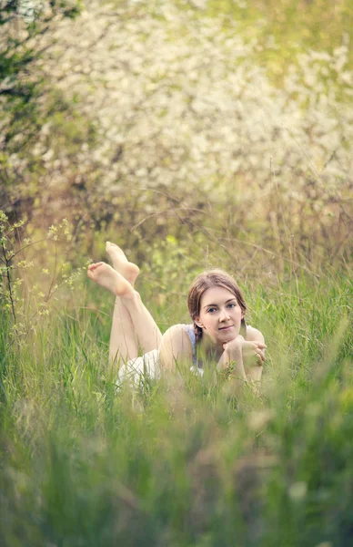 Das Mädchen liegt auf dem Gras im Frühlingswald — Stockfoto