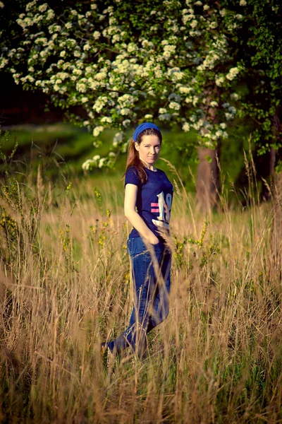 Сучасна дівчина в джинсах і футболка на тлі весняної природи. Обробка повідомлень . — стокове фото