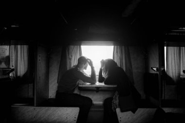 A man and a woman are sitting near a window in a train. B w photo clipart
