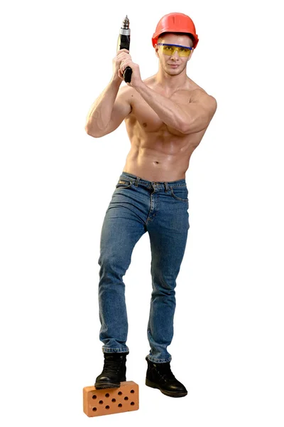 Athletic worker with a screwdriver in his hand, a red construction helmet and red brick building. — Stock Photo, Image