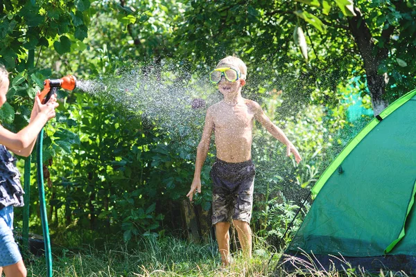 庭のホースから水をかけお互い暑い夏に遊ぶ女の子の男の子。男の子 Toning.Focus — ストック写真
