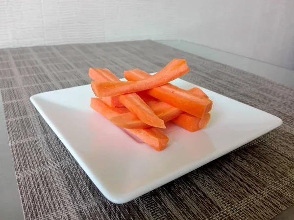 एक प्लेट में एक टेबल पर टुकड़े हुए गाजर — स्टॉक फ़ोटो, इमेज