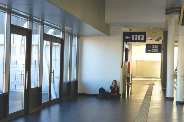 Osamělý cestovatel v budově železniční stanice. Dívka poslechu hudby ve sluchátkách. — Stock fotografie