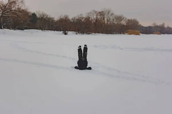 Jongen in de sneeuw ondersteboven neer. Van sneeuw benen alleen stok — Stockfoto