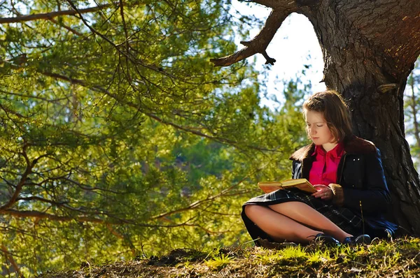 Une fille lit un livre dans une forêt d'automne — Photo