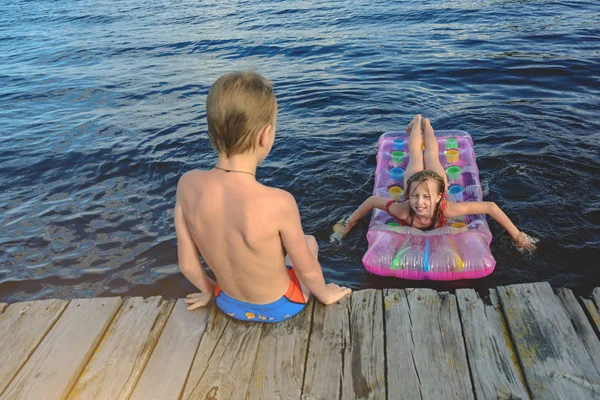 Діти стрибають на надувному матраці у воді — стокове фото