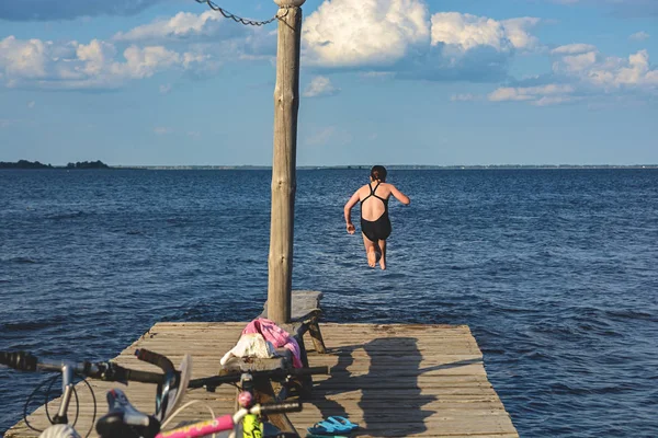 Девушка прыгает с деревянного моста на воду — стоковое фото