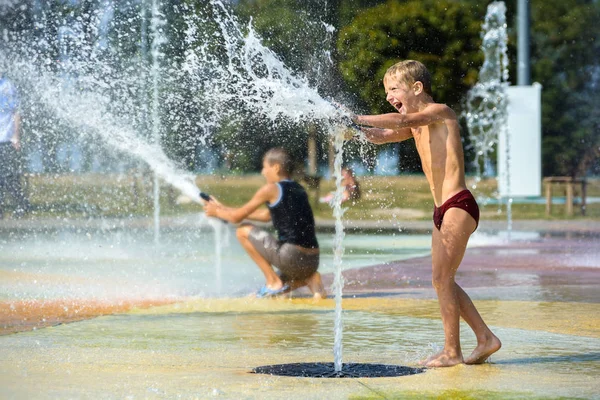 Children play with water in a fountain