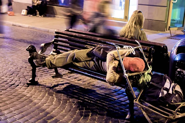 Een dakloze man slapen op een bankje 's nachts in de stad. Toning — Stockfoto