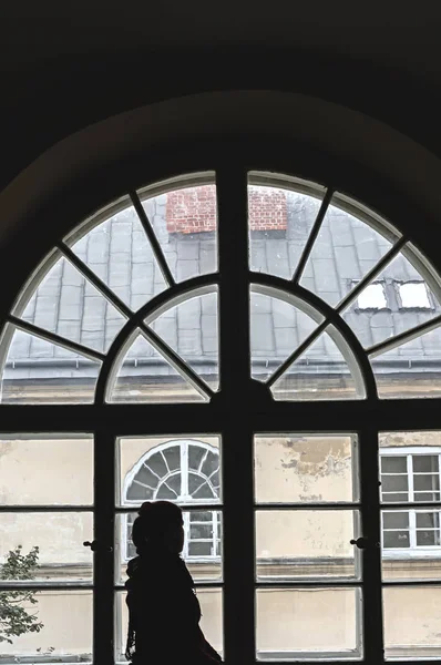 Σιλουέτα ενός κοριτσιού μπροστά από ένα παλιό μεγάλο παράθυρο. — Φωτογραφία Αρχείου