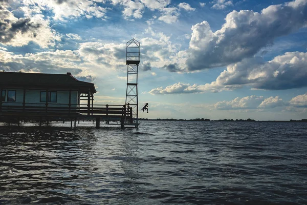 Un uomo sta saltando da una torre nel fiume — Foto Stock