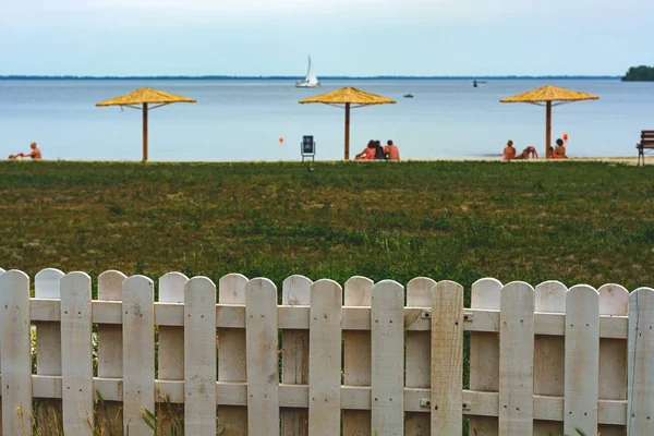 Пляжные зонтики из соломы на фоне воды и яхты — стоковое фото