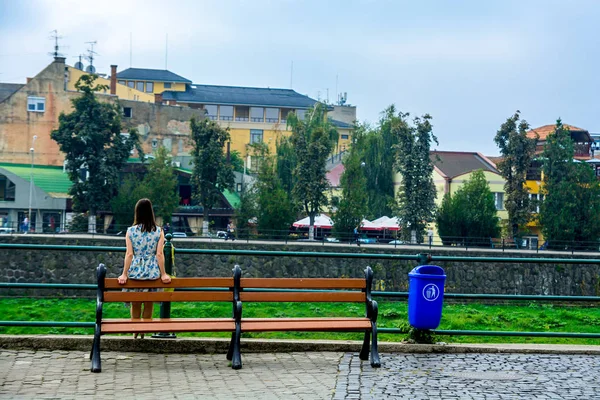 Дівчина захоплюється міста. Задній вид. Дівчина на лавці, на набережній річки Уж. — стокове фото