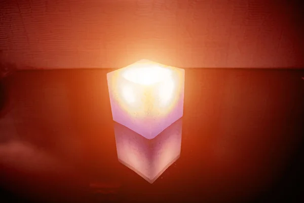 Горящая свеча в форме куба на красном фоне — стоковое фото