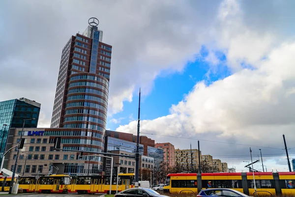 Varsóvia, Polônia - 29 de novembro de 2016: logotipo da Mercedes em um prédio de arranha-céus em Varsóvia. Rua com trânsito e bondes elétricos novos amarelos . — Fotografia de Stock