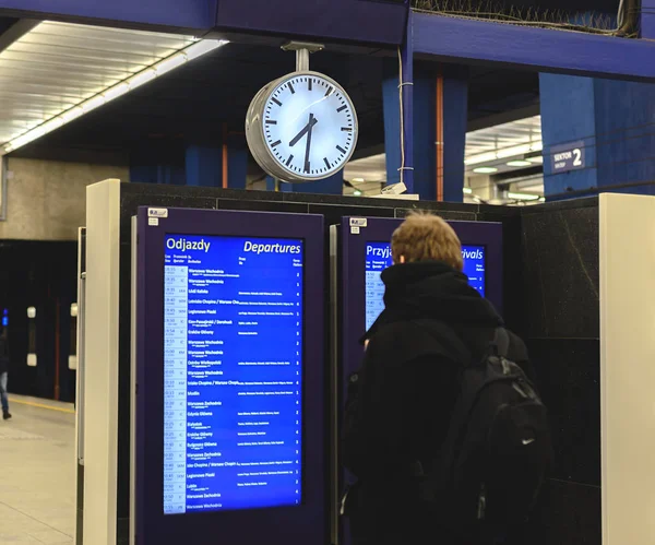 Varsovia, Polonia - 08 de diciembre de 2016: Un hombre está estudiando horarios de tren en una estación de Varsovia — Foto de Stock