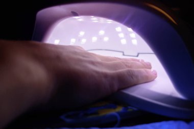 Kız tırnaklarını ultraviyole lambayla kurutuyor..