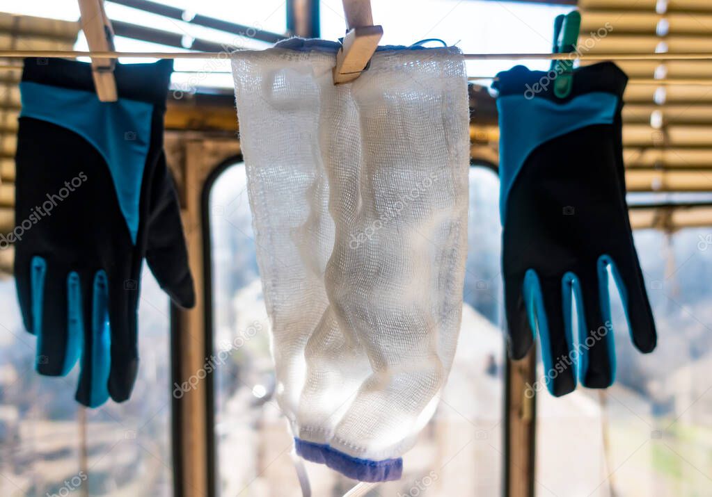 Medical mask and gloves hang on a balcony on a rope