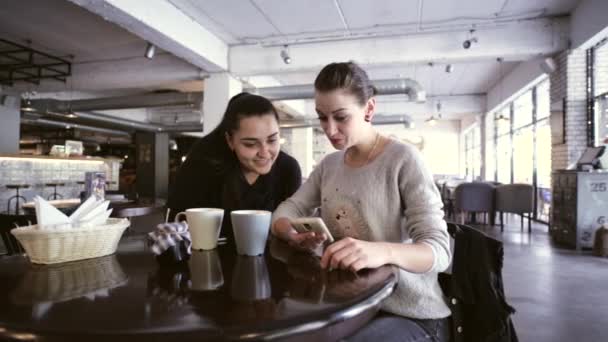 Duas jovens mulheres estão falando e usando o smartphone para mostrar algo engraçado . — Vídeo de Stock