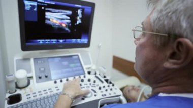 Doktor Bayan hasta inceden inceye gözden geçirmek için ultrason makinesi kullanıyor