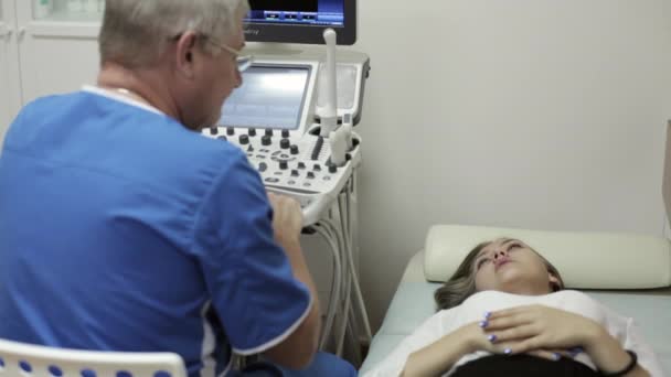 Αρσενικό γιατρό του μιλώντας με νεαρή γυναίκα ασθενή στο δωμάτιο διαγνωστικός υπέρηχος. — Αρχείο Βίντεο