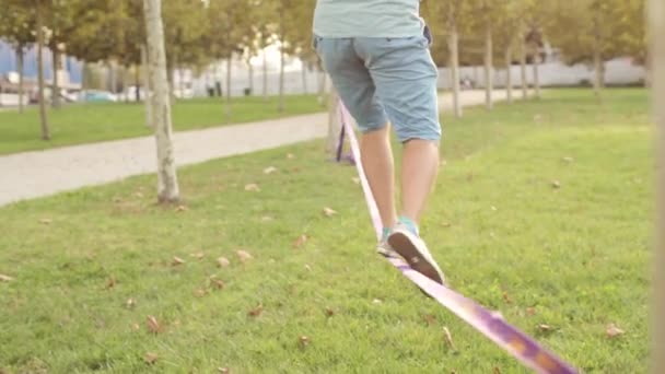 Guy walks on slackline at public park — Stock Video