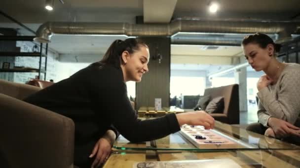 Två kvinnliga frends oman sitter i caféet och leker med brädspel. — Stockvideo