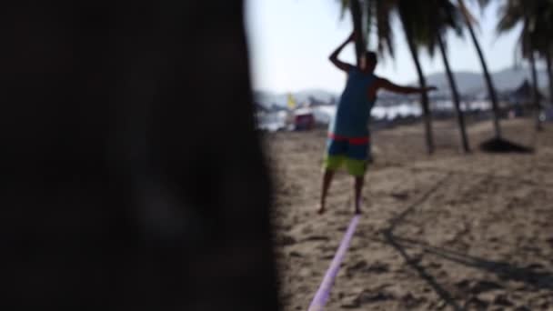 男人在松绳在海滩上保持平衡 — 图库视频影像